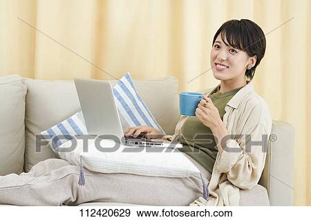 Stock Photo - Young Japanese woman working at home. Fotosearch