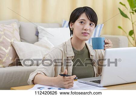 Stock Photograph - Young Japanese woman working at home. Fotosearch