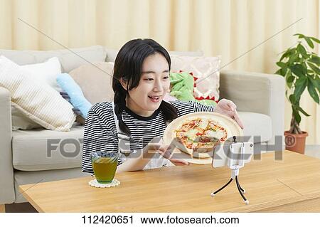 Stock Image - Young Japanese youtuber streaming at home. Fotosearch