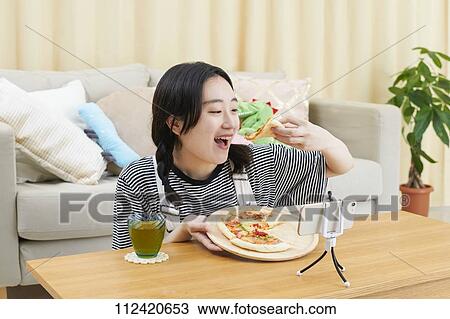 Stock Image - Young Japanese youtuber streaming at home. Fotosearch