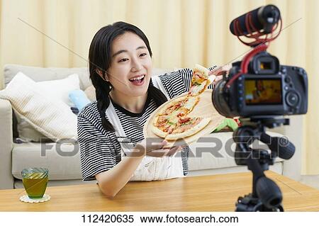 Stock Photography - Young Japanese youtuber streaming at home. Fotosearch