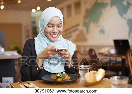 Stock Photo - Young South-east Asian woman eating at restaurant. Fotosearch