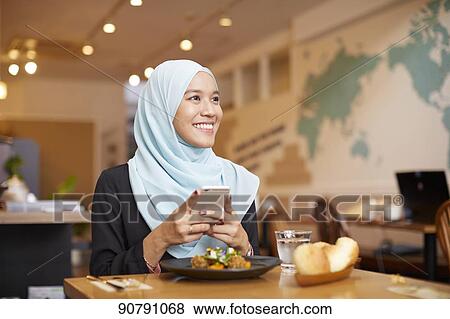 Stock Photo - Young South-east Asian woman eating at restaurant. Fotosearch
