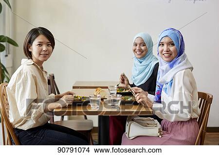 Picture - Young South-east Asian women eating at restaurant. Fotosearch