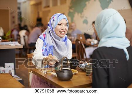 Stock Photo - Young South-east Asian women eating at restaurant. Fotosearch