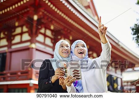 Stock Image - Young South-east Asian women enjoying sightseeing in Tokyo. Fotosearch
