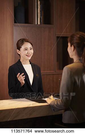 Picture - Young woman checking in at a hotel. Fotosearch