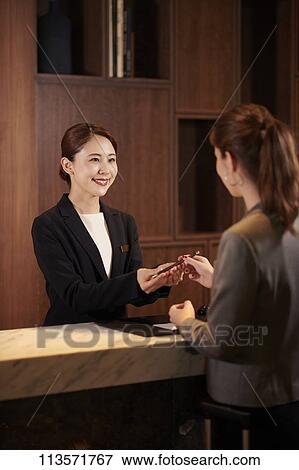 Stock Photo - Young woman checking in at a hotel. Fotosearch