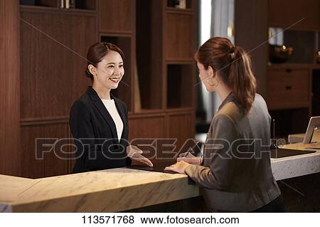 Stock Photo - Young woman checking in at a hotel. Fotosearch