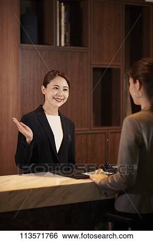 Stock Photograph - Young woman checking in at a hotel. Fotosearch