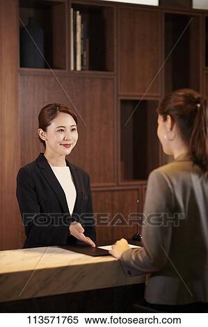 Stock Photography - Young woman checking in at a hotel. Fotosearch