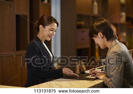 Stock Photography - Young woman checking in at hotel. Fotosearch