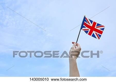 Hand holding flag against blue sky View Large Photo Image Stock Image - Hand holding flag against blue sky. Fotosearch