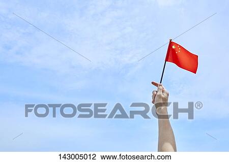 Hand holding flag against blue sky View Large Photo Image Stock Image - Hand holding flag against blue sky. Fotosearch