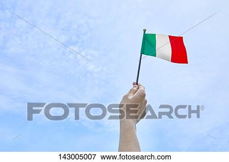 Stock Photo - Hand holding flag against blue sky. Fotosearch