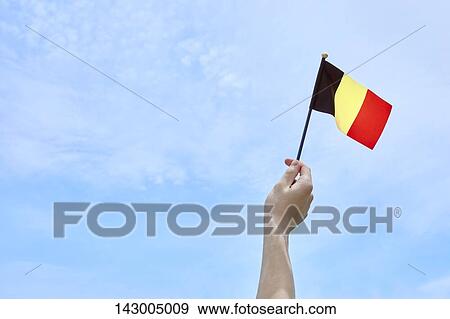 Stock Photo - Hand holding flag against blue sky. Fotosearch