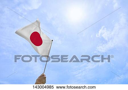 Hand holding flag against blue sky View Large Photo Image Stock Photography - Hand holding flag against blue sky. Fotosearch