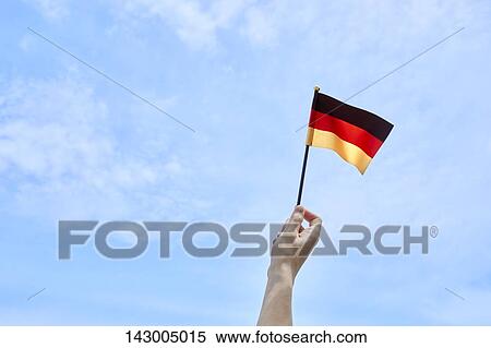 Hand holding flag against blue sky View Large Photo Image Stock Photography - Hand holding flag against blue sky. Fotosearch