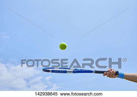 Hand holding tennis racket against blue sky View Large Photo Image Stock Photography - Hand holding tennis racket against blue sky. Fotosearch