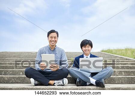 Stock Image - Happy Japanese father and son outdoors. Fotosearch