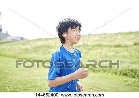 Stock Image - Happy Japanese teenager enjoying himself outdoors. Fotosearch