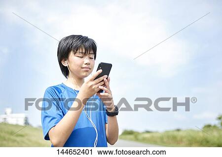Stock Image - Happy Japanese teenager enjoying himself outdoors. Fotosearch