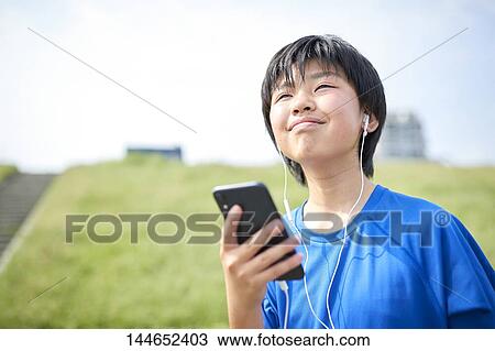 Stock Image - Happy Japanese teenager enjoying himself outdoors. Fotosearch
