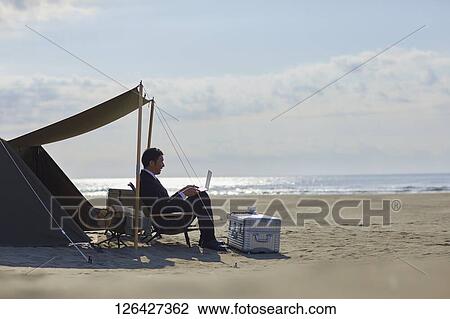 Stock Image - Japanese businessman working at the beach. Fotosearch