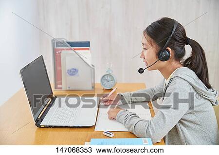 Stock Image - Japanese junior high schoolgirl studying remotely. Fotosearch