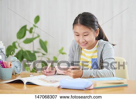 Stock Photo - Japanese junior high schoolgirl studying remotely. Fotosearch