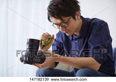 Japanese man cleaning camera at home View Large Photo Image Stock Photo - Japanese man cleaning camera at home. Fotosearch