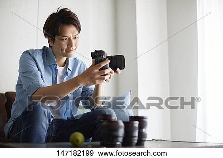 Japanese man cleaning camera at home View Large Photo Image Stock Photo - Japanese man cleaning camera at home. Fotosearch