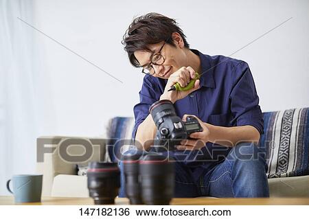 Stock Photograph - Japanese man cleaning camera at home. Fotosearch