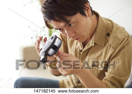 Stock Photography - Japanese man cleaning fishing rod at home. Fotosearch