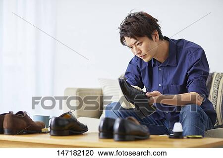 Stock Image - Japanese man cleaning shoes at home. Fotosearch