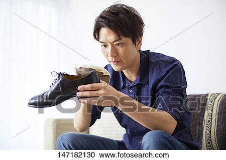 Stock Image - Japanese man cleaning shoes at home. Fotosearch