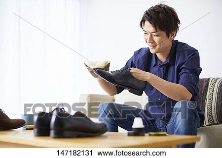 Stock Image - Japanese man cleaning shoes at home. Fotosearch