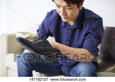 Stock Photo - Japanese man cleaning shoes at home. Fotosearch