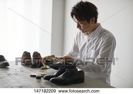 Stock Photo - Japanese man cleaning shoes at home. Fotosearch