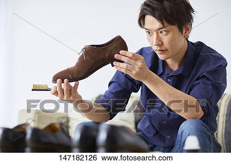 Stock Photograph - Japanese man cleaning shoes at home. Fotosearch