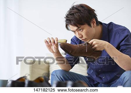 Stock Photography - Japanese man cleaning shoes at home. Fotosearch