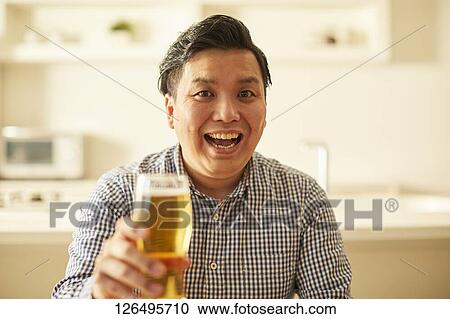Stock Image - Japanese man drinking at home remote drinking. Fotosearch