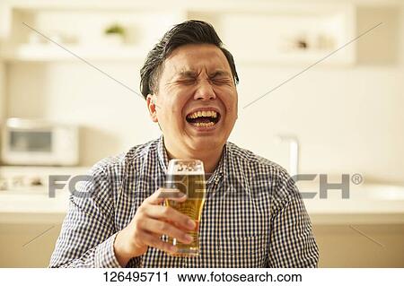 Stock Image - Japanese man drinking at home remote drinking. Fotosearch