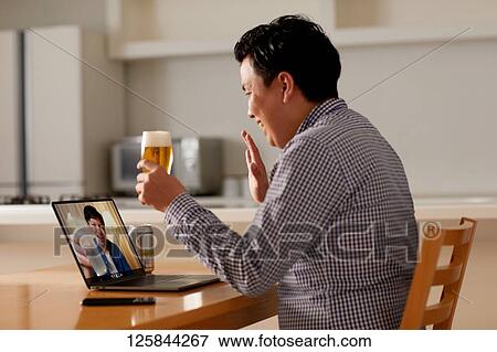 Stock Photo - Japanese man drinking at home remote drinking. Fotosearch