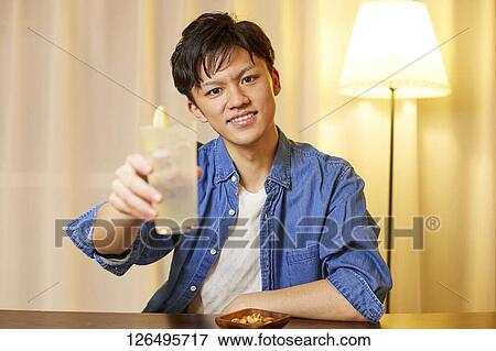 Stock Photo - Japanese man drinking at home remote drinking. Fotosearch