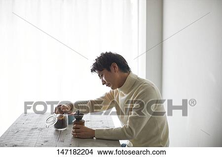 Picture - Japanese man making coffee at home. Fotosearch