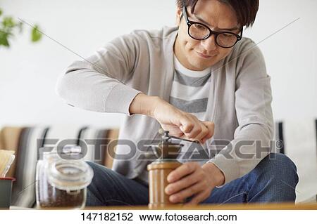 Stock Image - Japanese man making coffee at home. Fotosearch