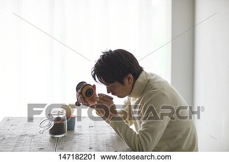 Stock Image - Japanese man making coffee at home. Fotosearch