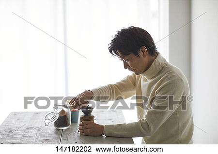 Stock Image - Japanese man making coffee at home. Fotosearch