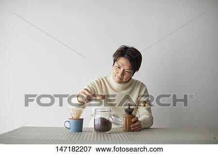 Stock Photo - Japanese man making coffee at home. Fotosearch